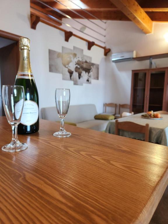 una bottiglia di vino e due bicchieri su un tavolo di Appartamento a due passi dal mare a Càbras