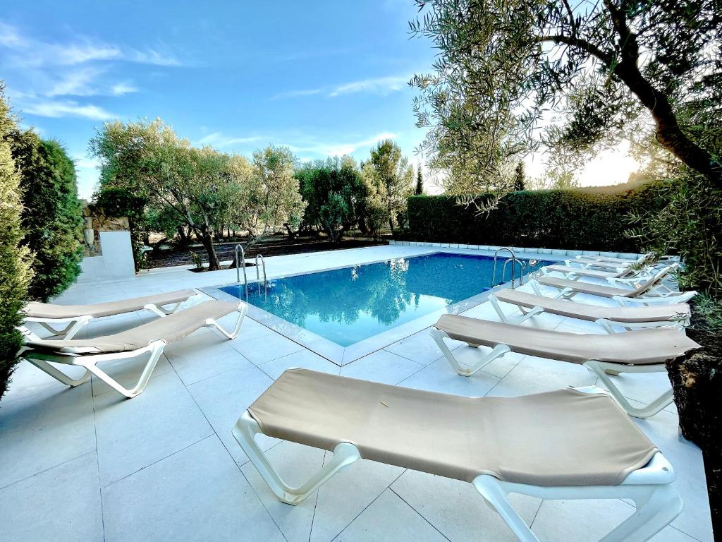 a row of lounge chairs next to a swimming pool at Hacienda Sierra del Pozo -Especial Grupos- in Pozo Alcón