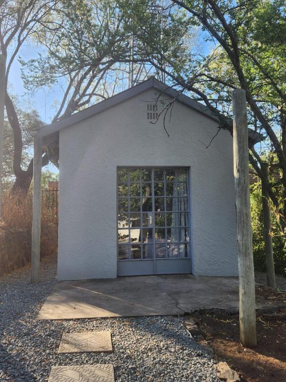 - un petit bâtiment blanc avec une grande porte dans l'établissement Peace of Nature, à Bloemfontein