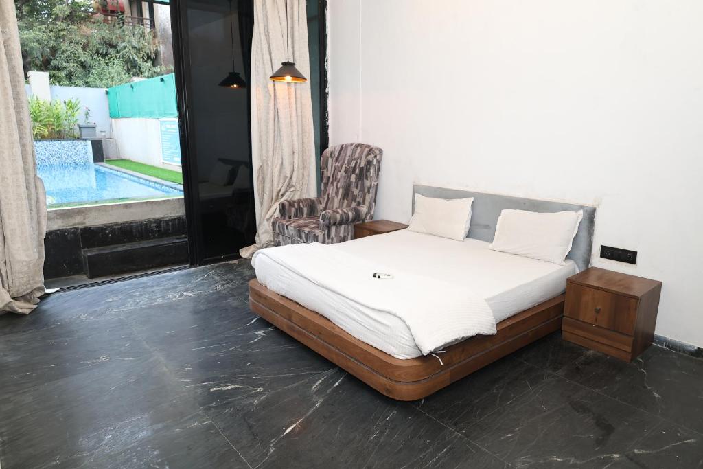 1 dormitorio con 1 cama, 1 silla y 1 ventana en Shalimar Royal Villa, en Lonavala