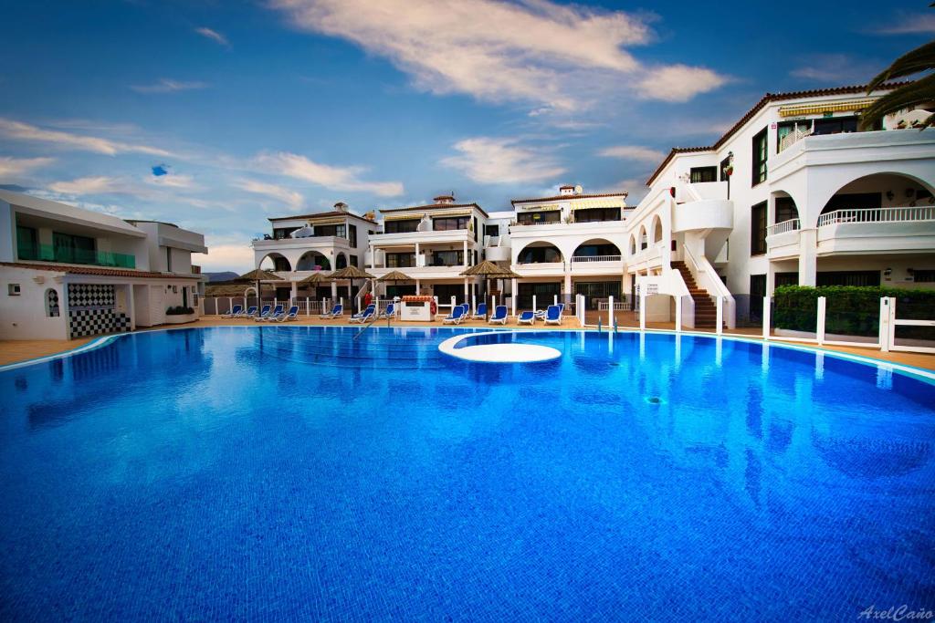 Una gran piscina azul frente a unos edificios. en Waves of Tranquility Residence, en San Miguel de Abona