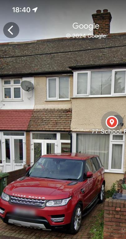 un coche rojo estacionado frente a una casa en Dagenham Budget House, en Dagenham