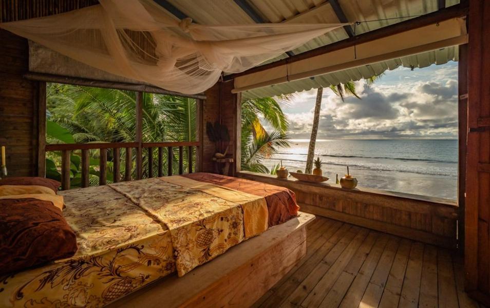 cabaña tellin في Termales - agua caliente - nuqui: غرفة نوم مع سرير وإطلالة على المحيط