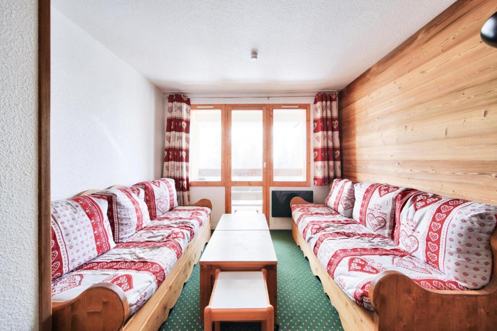 une chambre avec des canapés rouges et blancs et une table dans l'établissement Résidence Le Hameau du Sauget - maeva Home - Appartement 2 pièces 7 personnes - Sélection MAE-2914, à La Plagne Tarentaise
