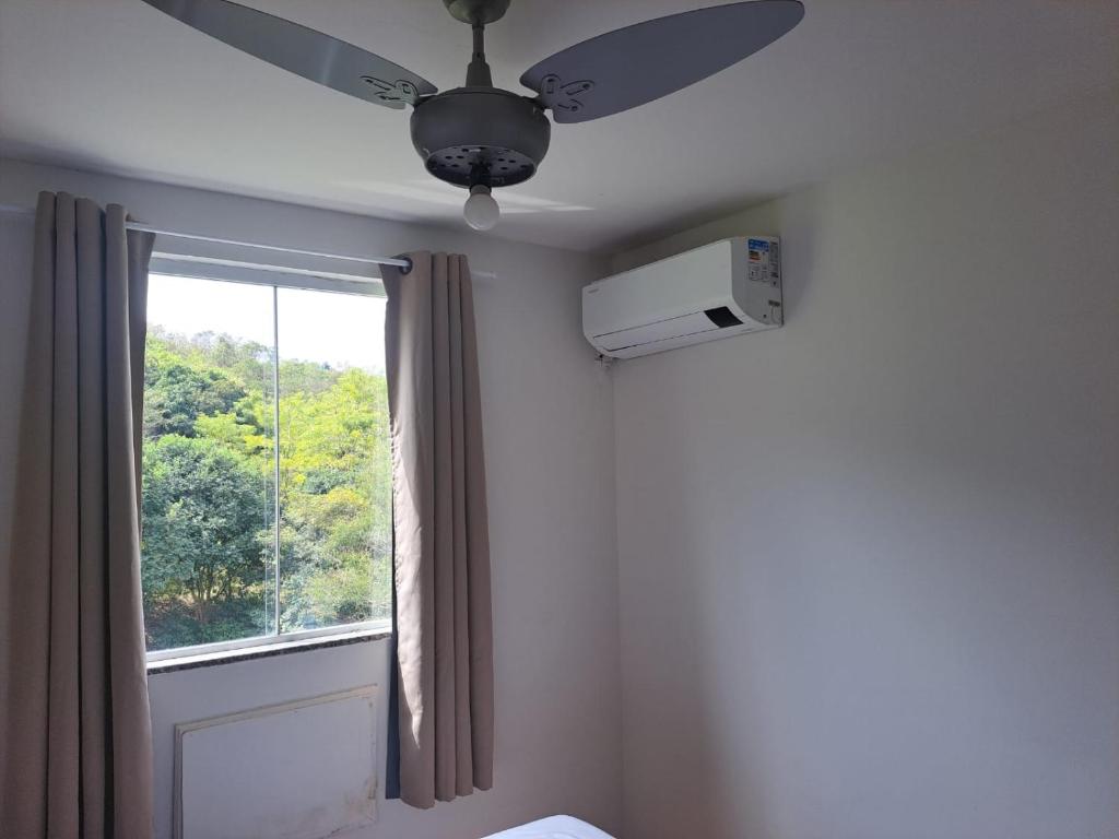 a bedroom with a ceiling fan and a window at Margaça Condomínio Califórnia in Rio de Janeiro