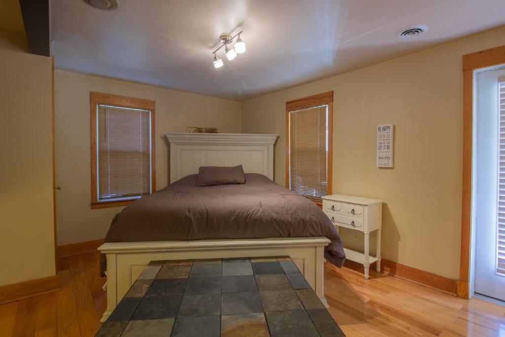 a bedroom with a bed and a dresser and windows at Stay In Ohiopyle in town by the GAP trail in Farmington