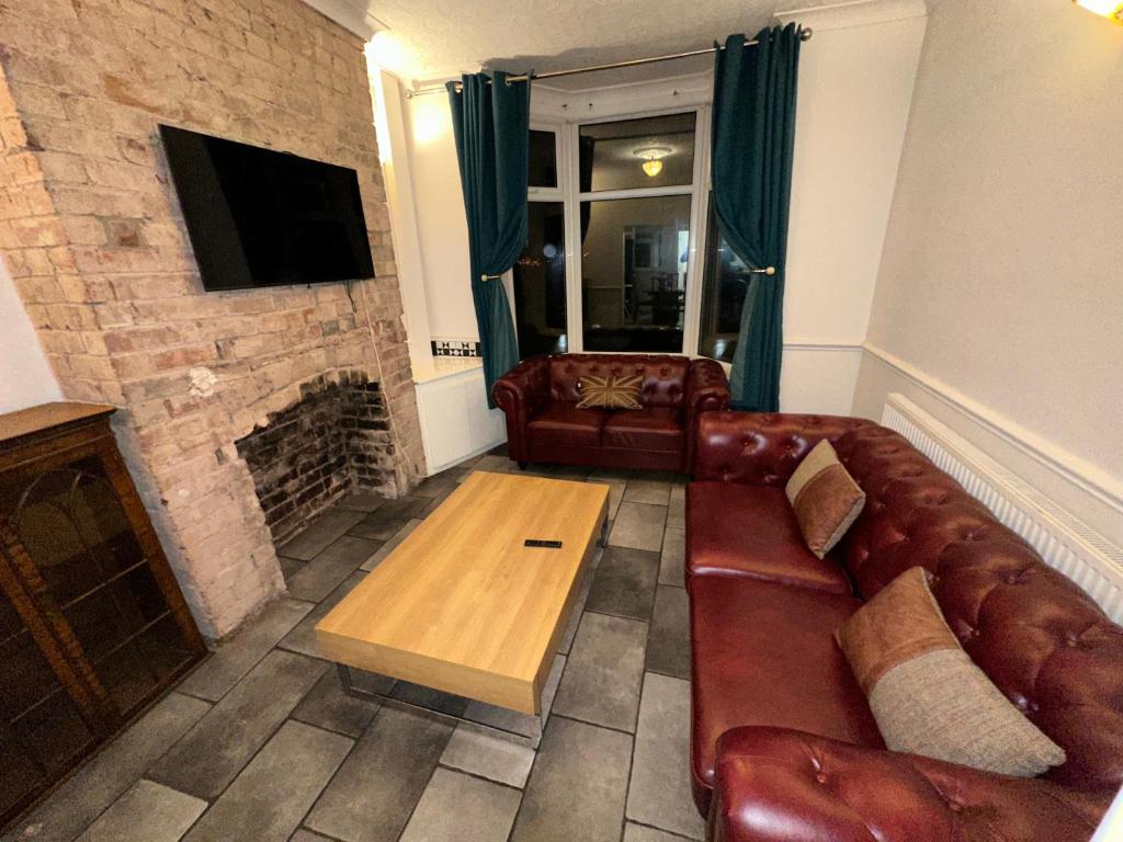 a living room with a leather couch and a fireplace at Bolsover Castle View in Bolsover