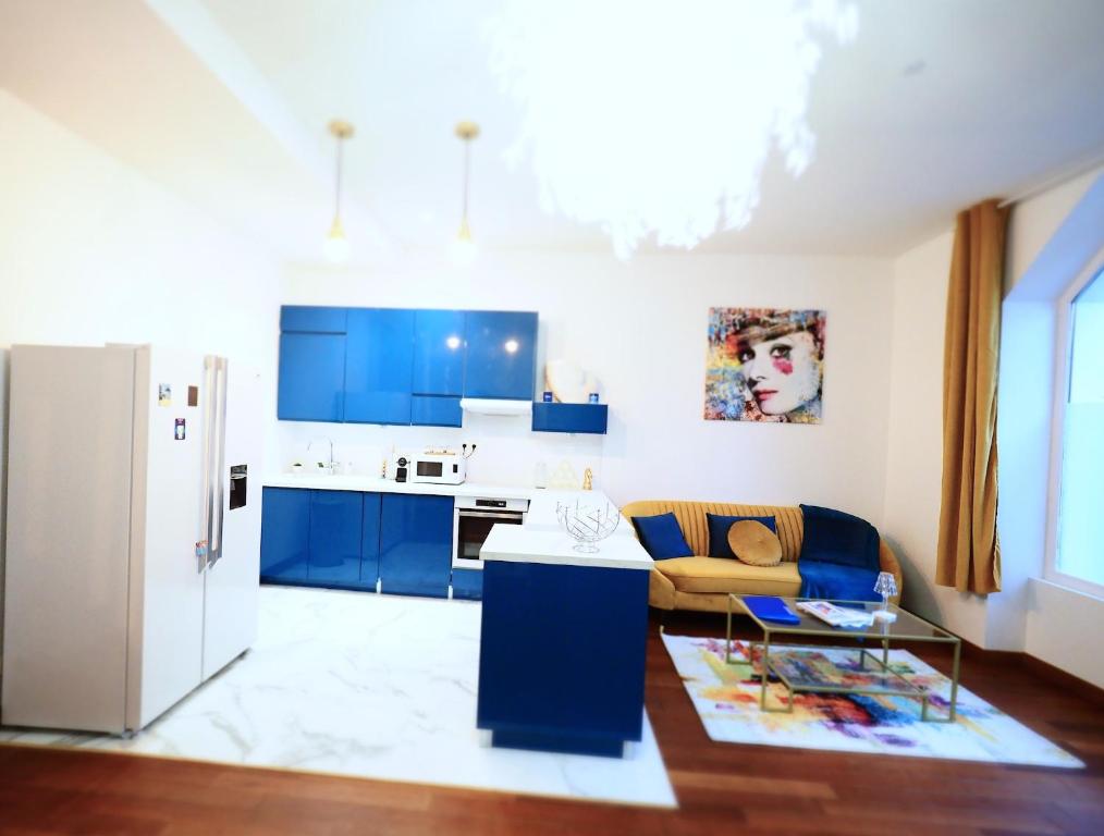 La cuisine est équipée de placards bleus et d'un réfrigérateur blanc. dans l'établissement LE PATIO LAFAYETTE Appartement de Standing coeur de ville, à Vichy