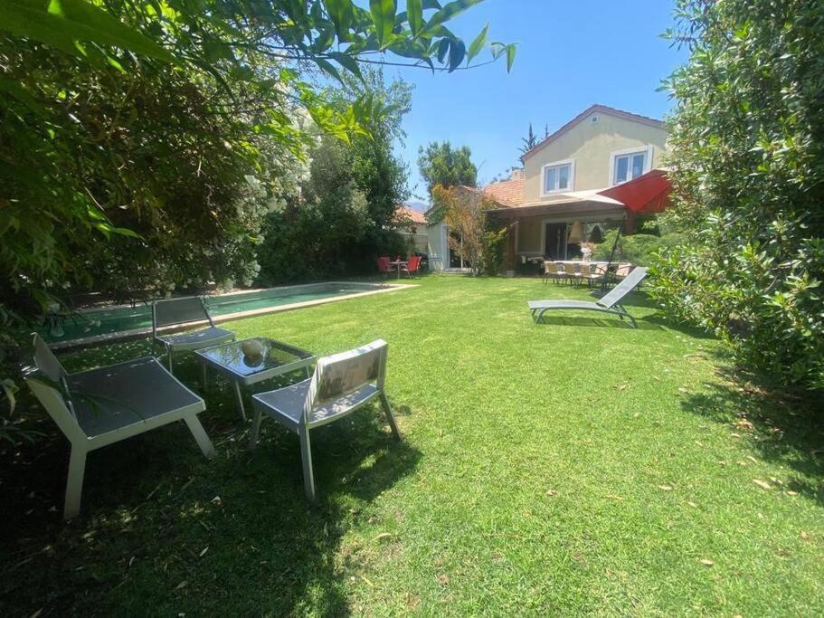 a yard with two benches and a table and a house at Casa Amoblada en chicureo in Chicureo Abajo