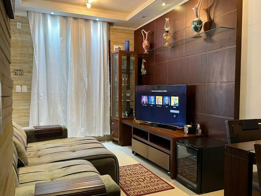 a living room with a television on a desk at Triplex c/ hidro 15 min do Praia de Belas e Barra Shopping in Porto Alegre