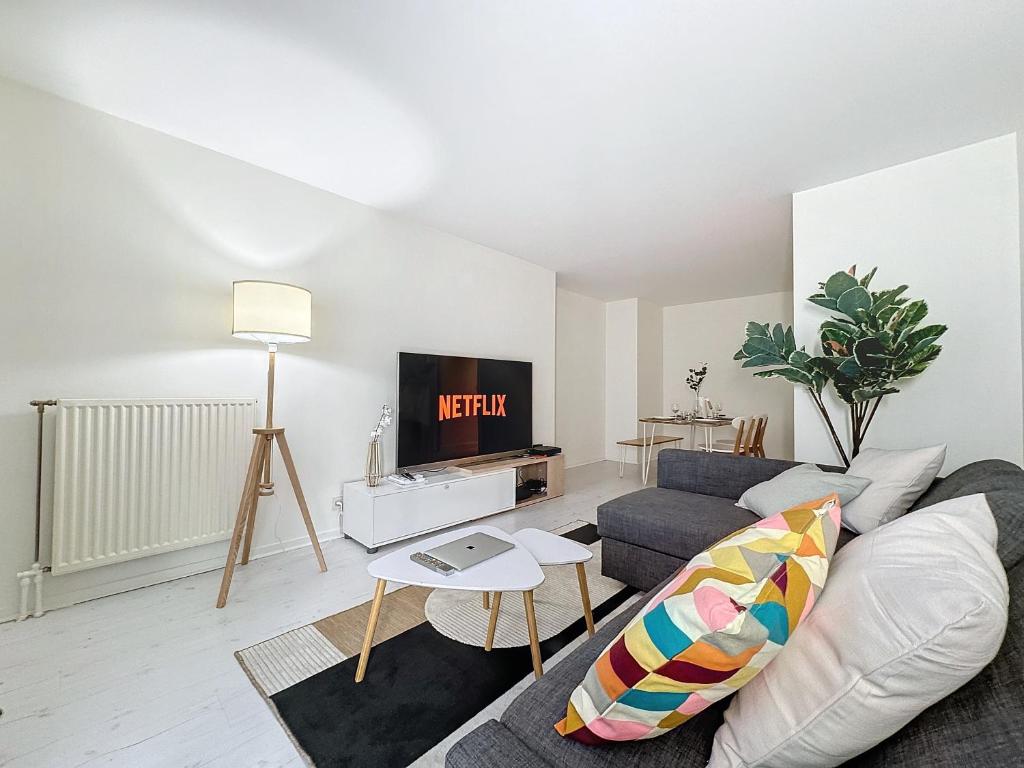a living room with a couch and a tv at Chaleureux et spacieux - Paris - Stade de France in Saint-Denis
