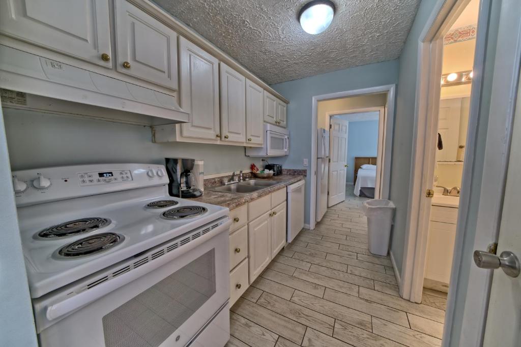 a kitchen with white cabinets and a white stove top oven at Pineapple Villas in Panama City Beach