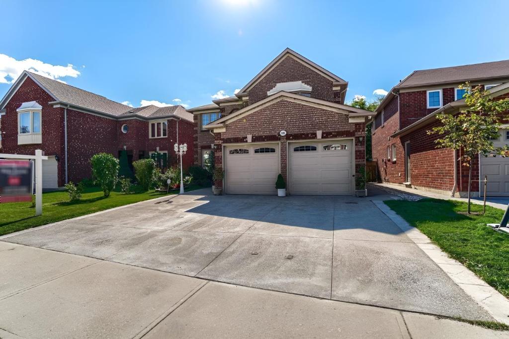 a house with two garage doors on a driveway at Deluxe King Size Ensuite bed room near the airport in Mississauga