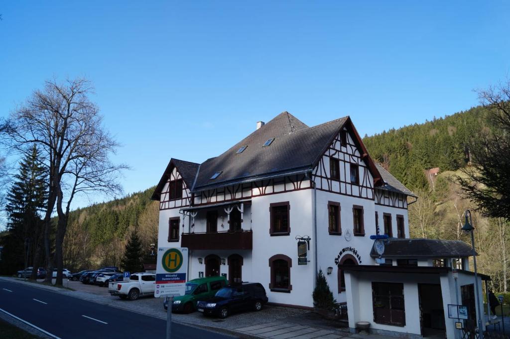 biały budynek z czarnym dachem przy drodze w obiekcie Gasthof und Pension Hammerschänke w mieście Wildenthal