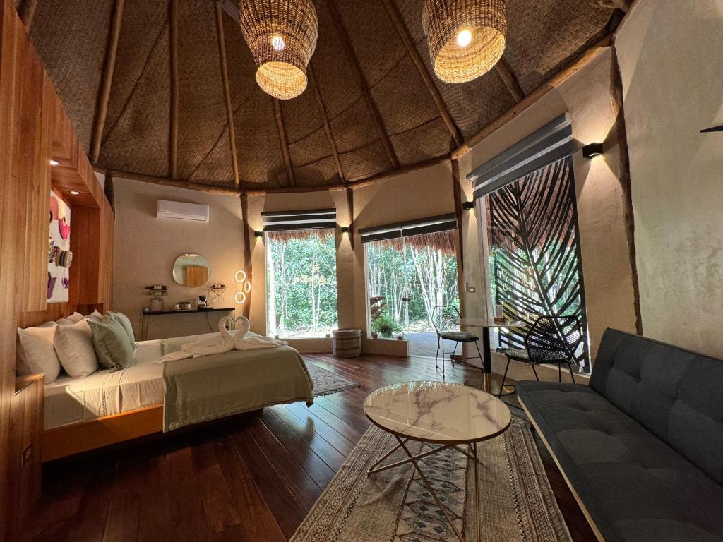 a bedroom with a bed and a couch and a table at Casa Kaan Calakmul in Xpujil