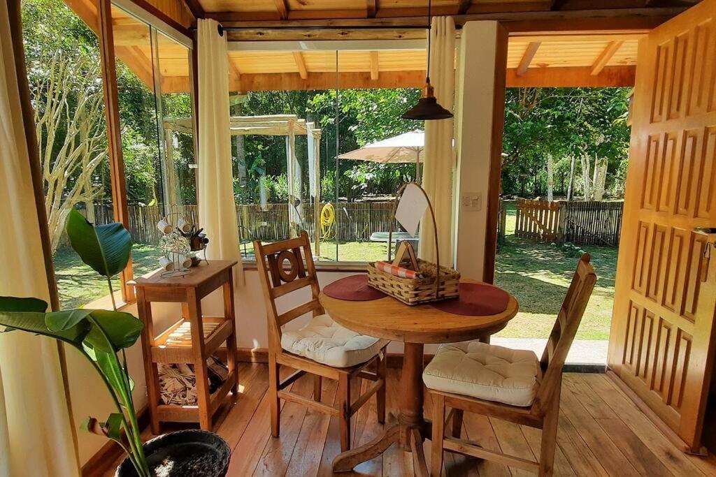 ein Esszimmer mit einem Tisch und Stühlen sowie eine Veranda in der Unterkunft Chalé Jasmim in Santo Antônio do Pinhal