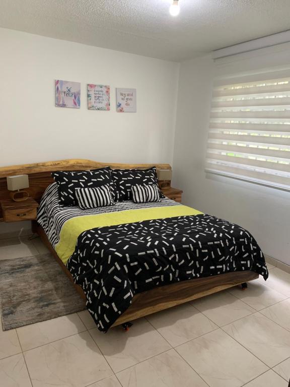 a bedroom with a bed with black and white sheets at Bellísimos apartamentos céntricos en La Mesa in La Mesa