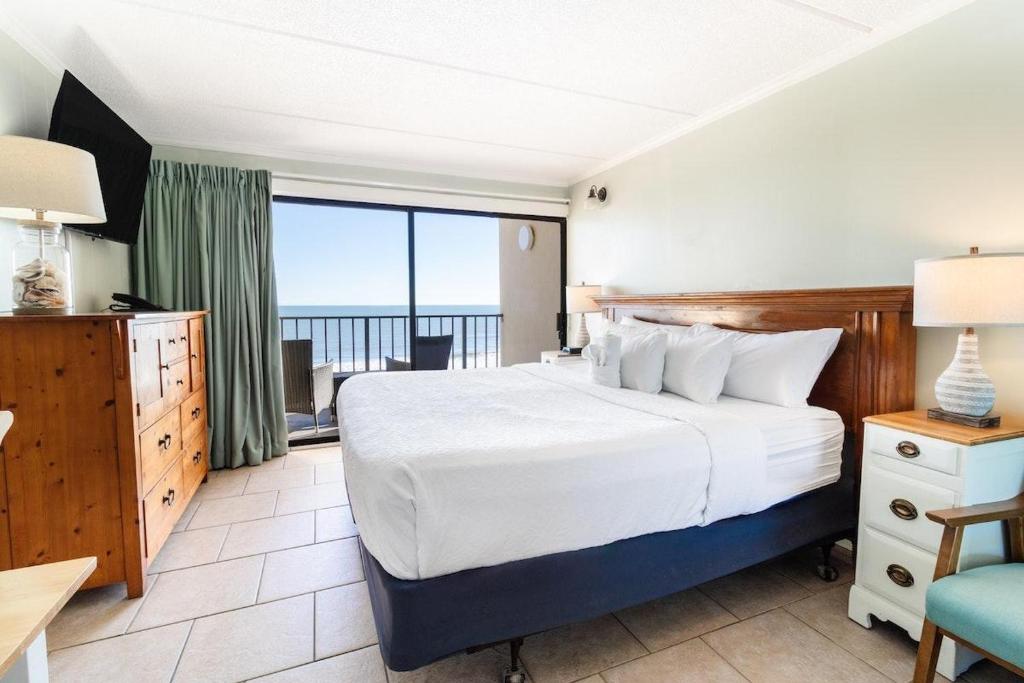 Un dormitorio con una gran cama blanca y un balcón. en Majestic Seascape 6th Flr Oceanfront King Room, en Pawleys Island