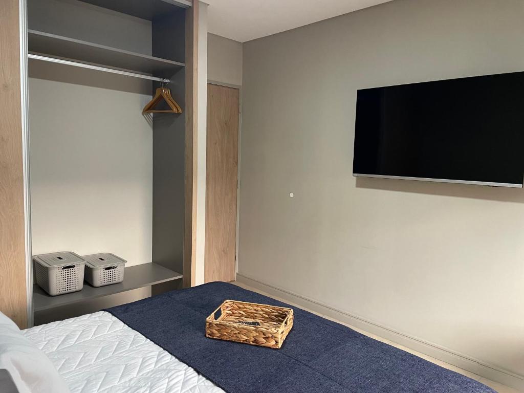 ein Schlafzimmer mit einem Bett und einem Flachbildfernseher an der Wand in der Unterkunft Departamento céntrico Belgrano II in San Salvador de Jujuy