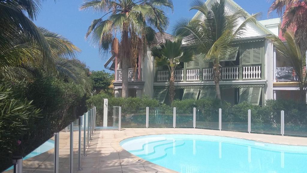 a swimming pool in front of a house with palm trees at Passiflora in Orient Bay