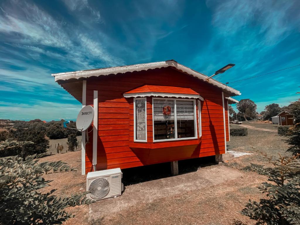 una pequeña casa roja con ventana y ventilador en Cabañas Los Queltehues, en Chacao Viejo