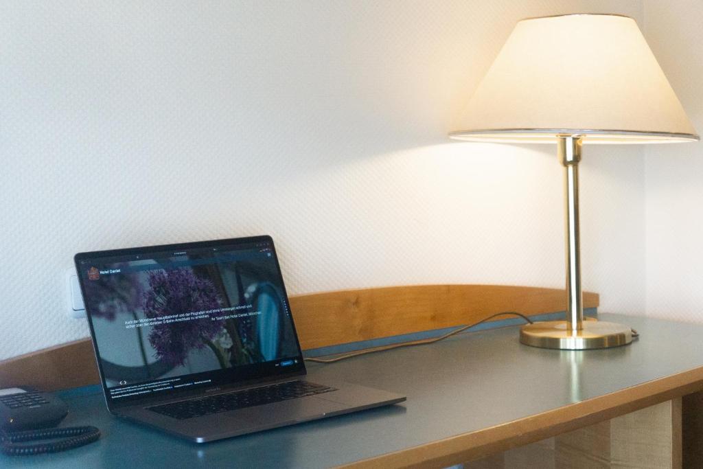 a laptop computer sitting on a desk next to a lamp at Hotel Daniel in Munich