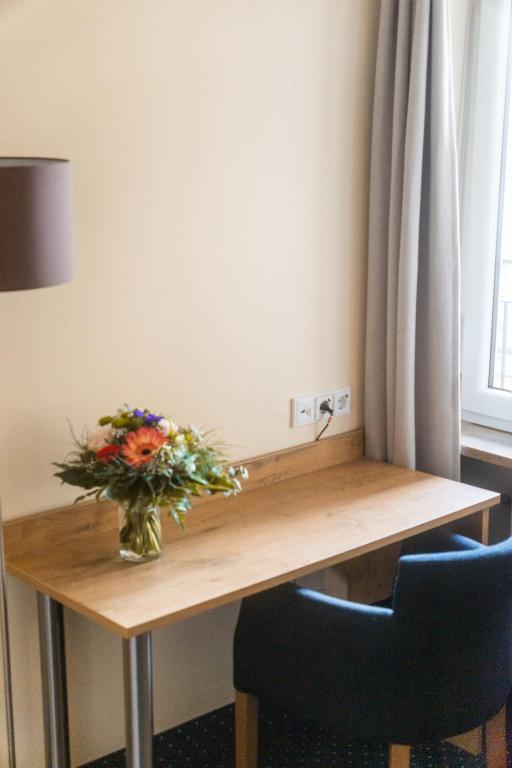 a vase of flowers on a wooden table with two chairs at Hotel Daniel in Munich