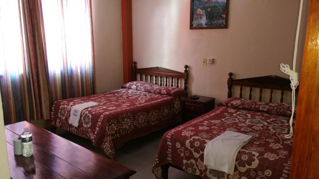 a hotel room with two beds and a table at Hotel y Bungalows Olivares in Acapulco