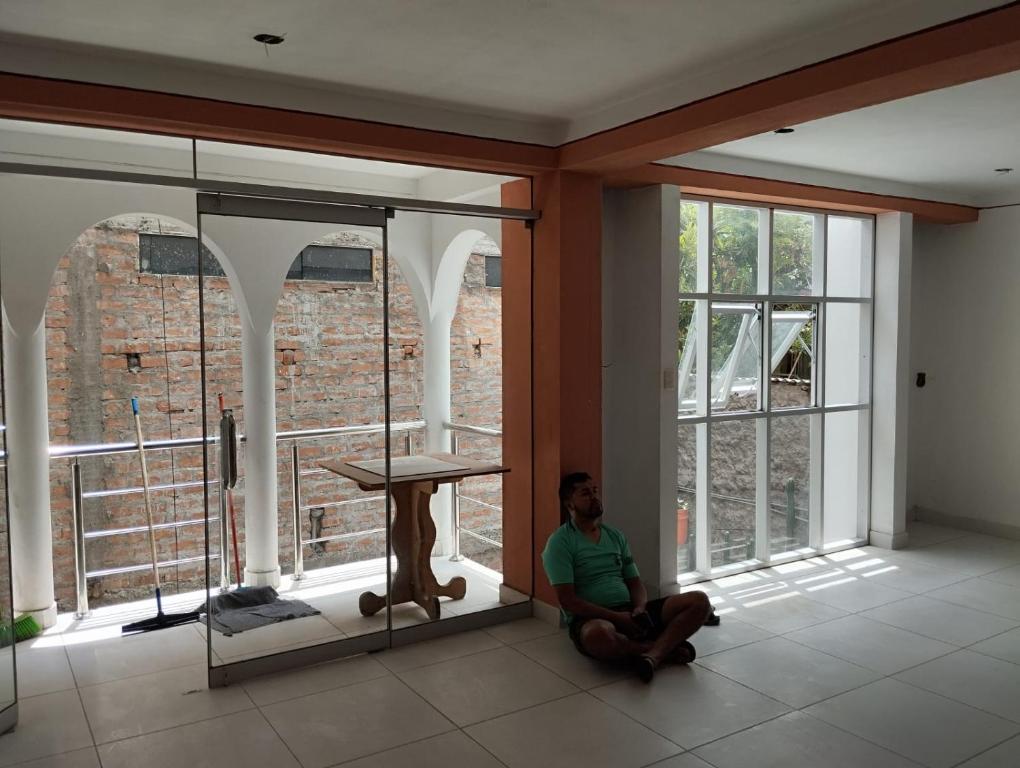 a man sitting on the floor in a room with windows at Kutimuy in Ayacucho