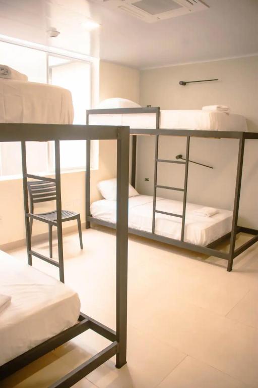 een kamer met 2 stapelbedden en een stoel bij Hotel Amazonas Suite, Habitación con literas in Nueva Loja