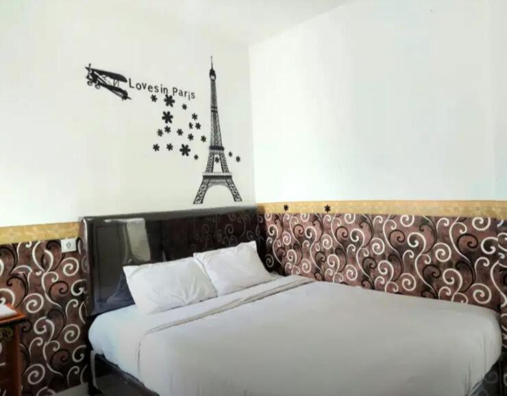 a bedroom with a bed and a sign with the eiffel tower at Aeropolis Apartemen in Teko