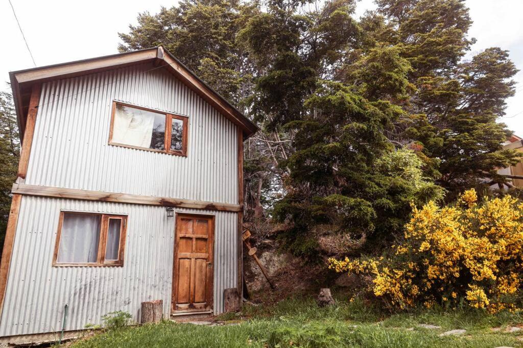 uma pequena casa branca com uma janela e uma porta em Cabaña Dakota, Ushuaia em Ushuaia