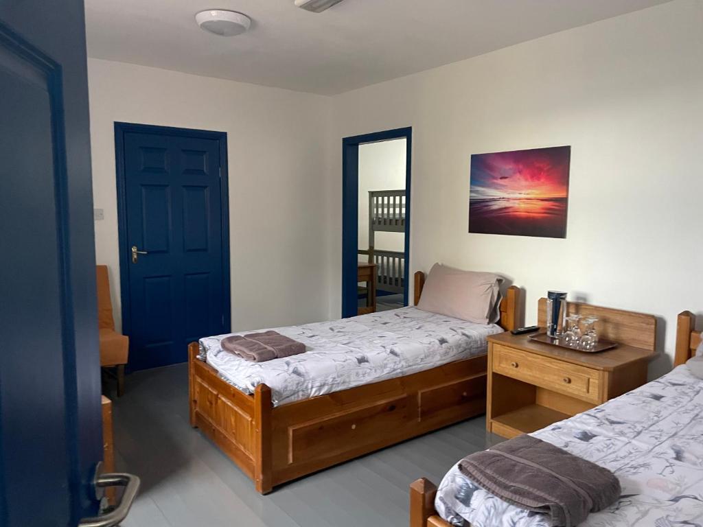 a bedroom with two beds and a blue door at Coastguard Lodge Hostel at Tigh TP in Dingle