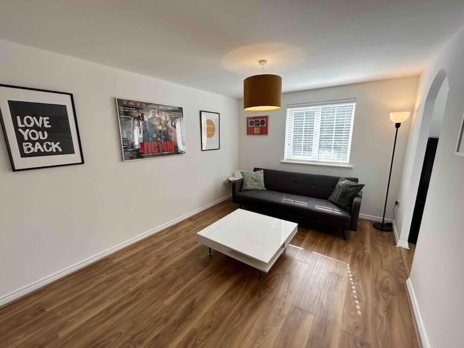 ein Wohnzimmer mit einem schwarzen Sofa und einem Tisch in der Unterkunft 1 Bed Greater London Flat next to Station & Free Parking in Romford