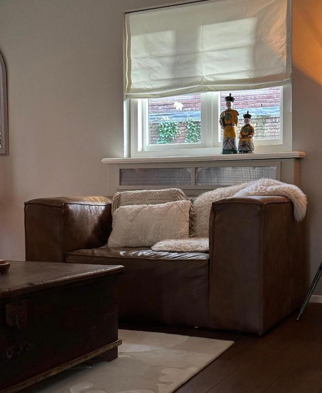 a living room with a brown leather couch and a window at Sterlogies Cityhouse Madame Agaath in Leeuwarden