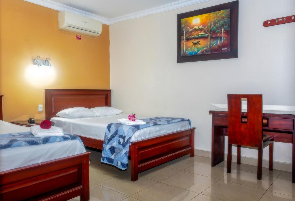 a bedroom with two beds and a desk and a chair at Airport Hotel Guayaquil in Guayaquil