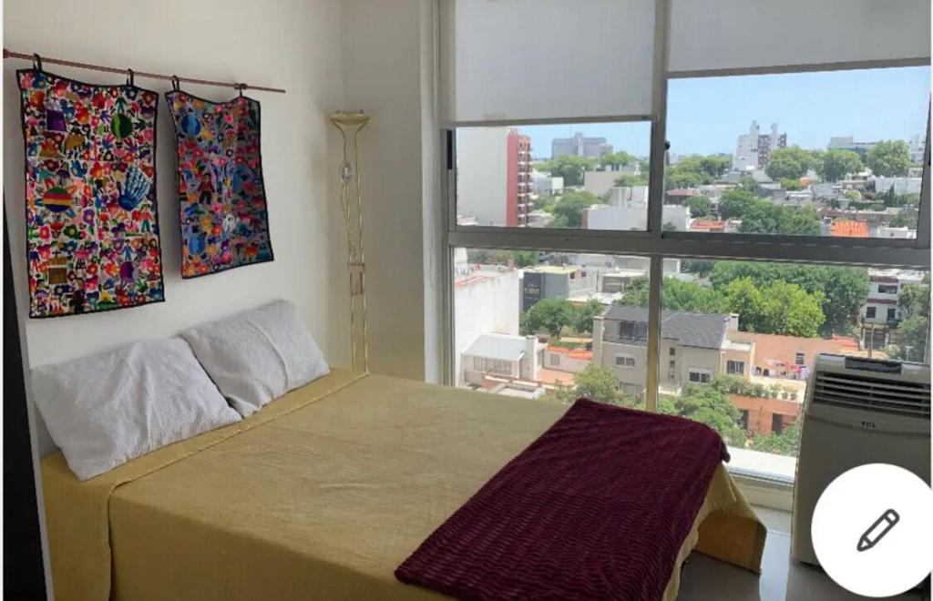 ein Schlafzimmer mit einem Bett und einem großen Fenster in der Unterkunft Studio Park in Montevideo