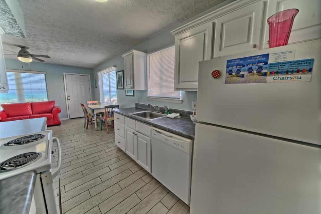 a kitchen with a white refrigerator and a dining room at Pineapple Villas in Panama City Beach