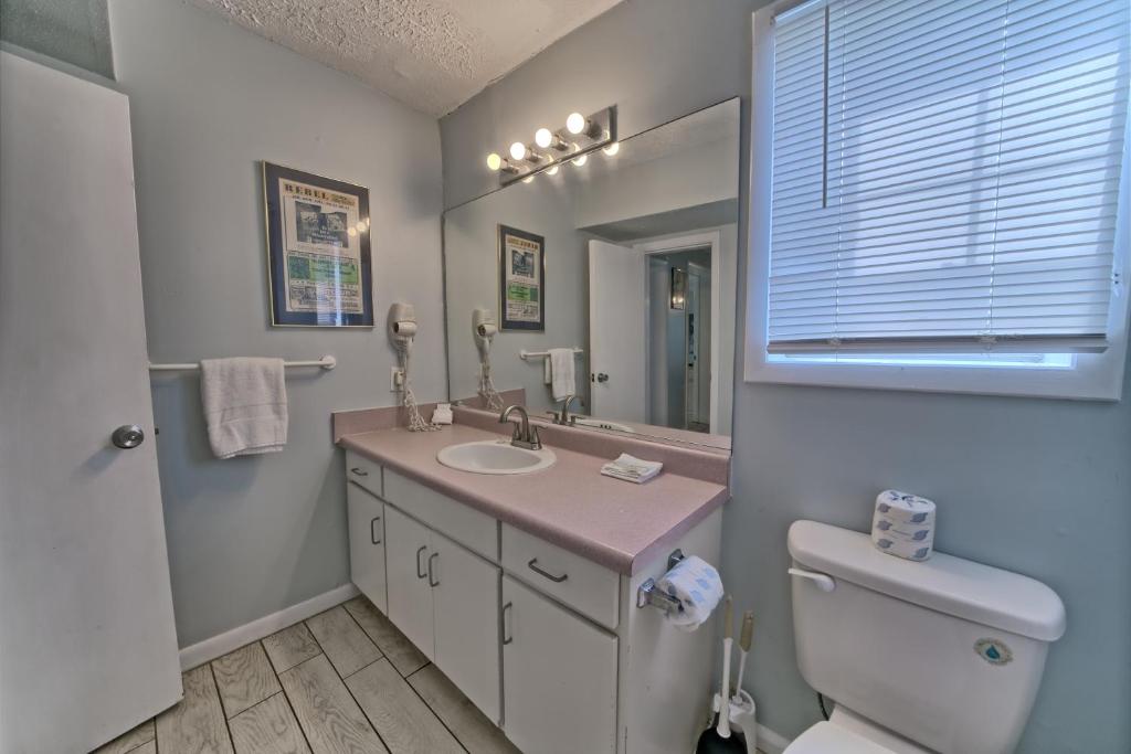 a bathroom with a sink and a toilet and a mirror at Pineapple Villas in Panama City Beach