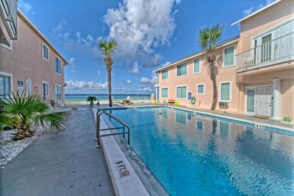 a swimming pool in front of a building with palm trees at Pineapple Villas in Panama City Beach