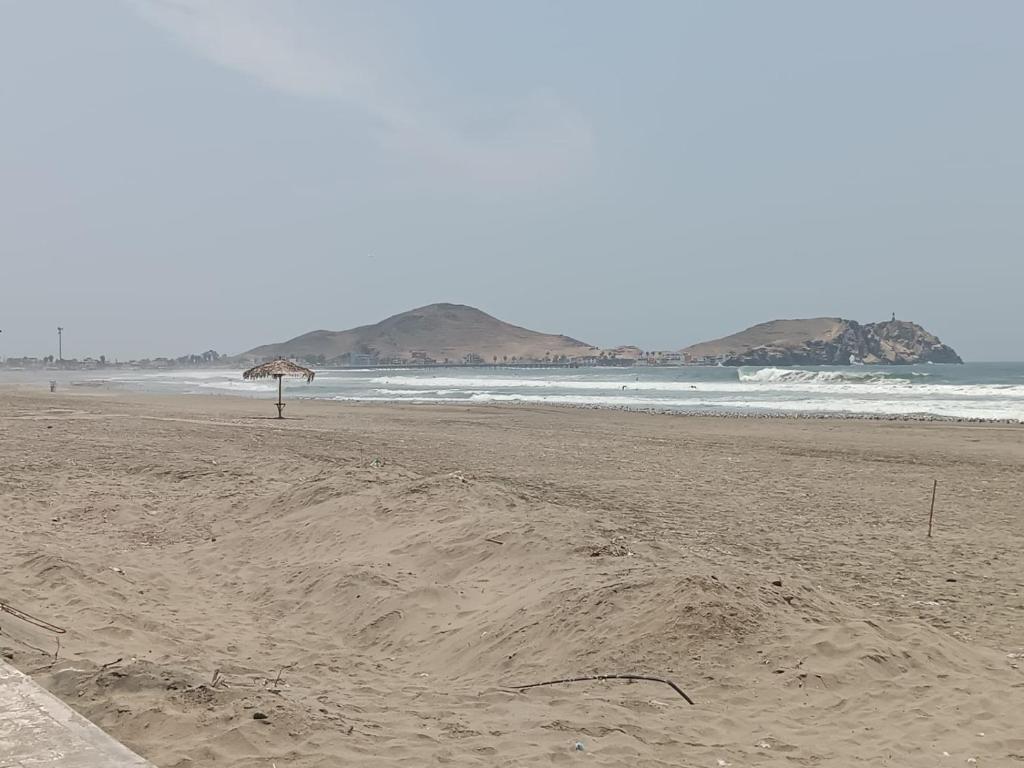 uma praia com um guarda-sol e o oceano em Departamentos de playa em Cerro Azul