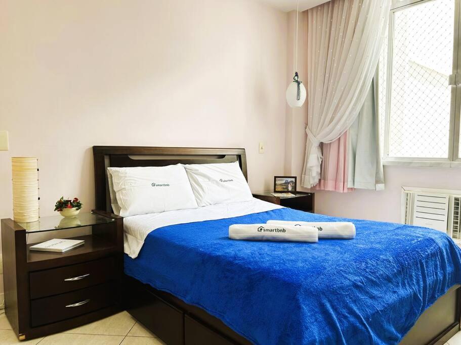 a bedroom with a large bed with a blue blanket at Charme do Leme in Rio de Janeiro