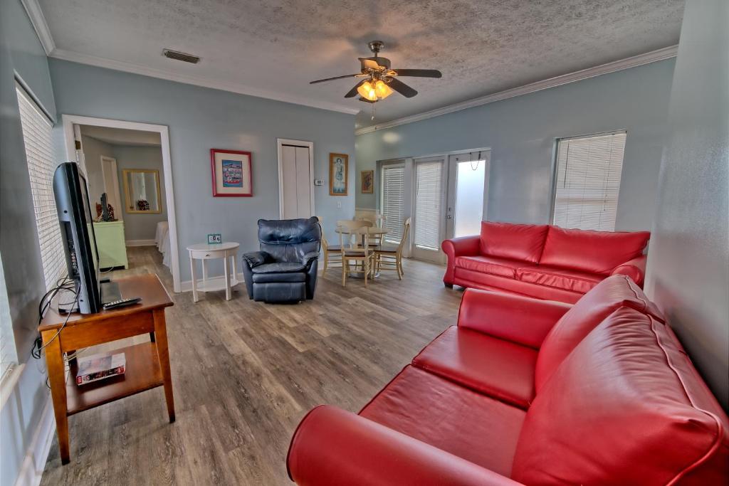 a living room with a red couch and a tv at Pineapple Villas in Panama City Beach