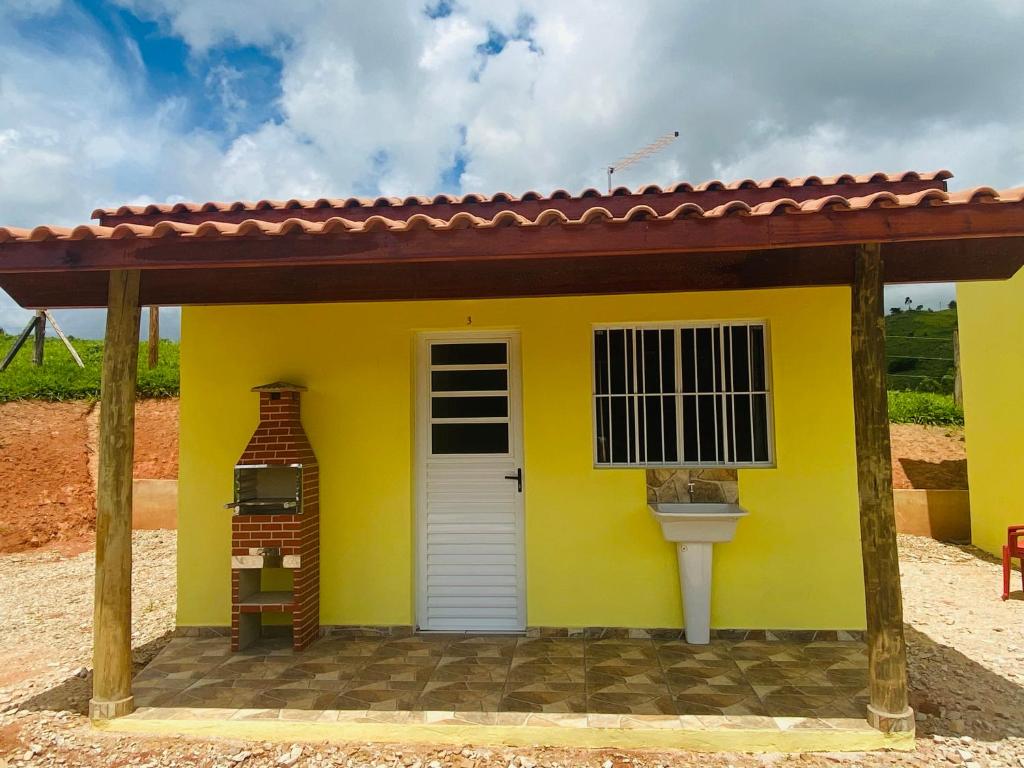 een klein geel huis met een rood dak bij Pousada Helena e Heloá in Serra Negra