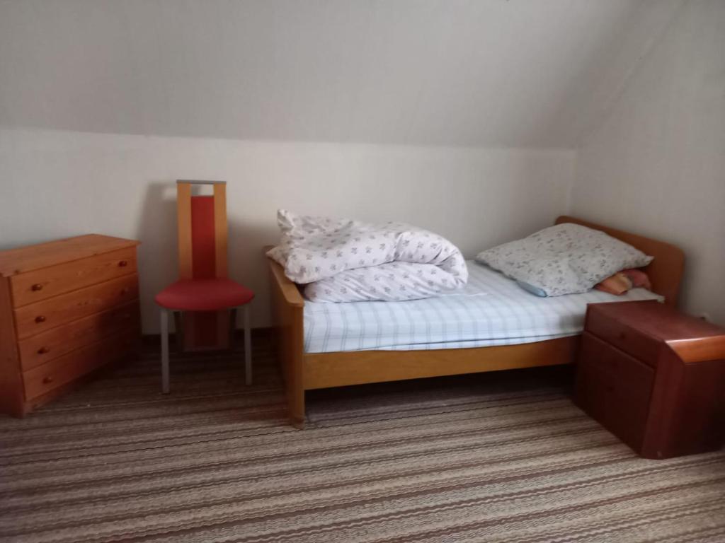 - une petite chambre avec un lit et un fauteuil rouge dans l'établissement Ferienhaus Dobbenland, à Krummhörn