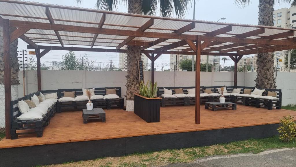 a pergola with couches and tables on a wooden deck at Cabañas Pinamar in La Serena