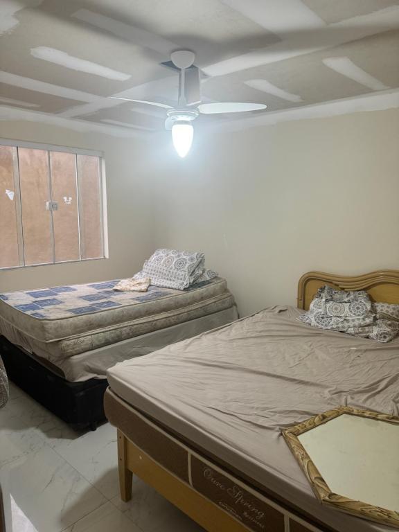 two beds in a room with a ceiling fan at Casa 3 quartos portinho Cabo Frio in Cabo Frio