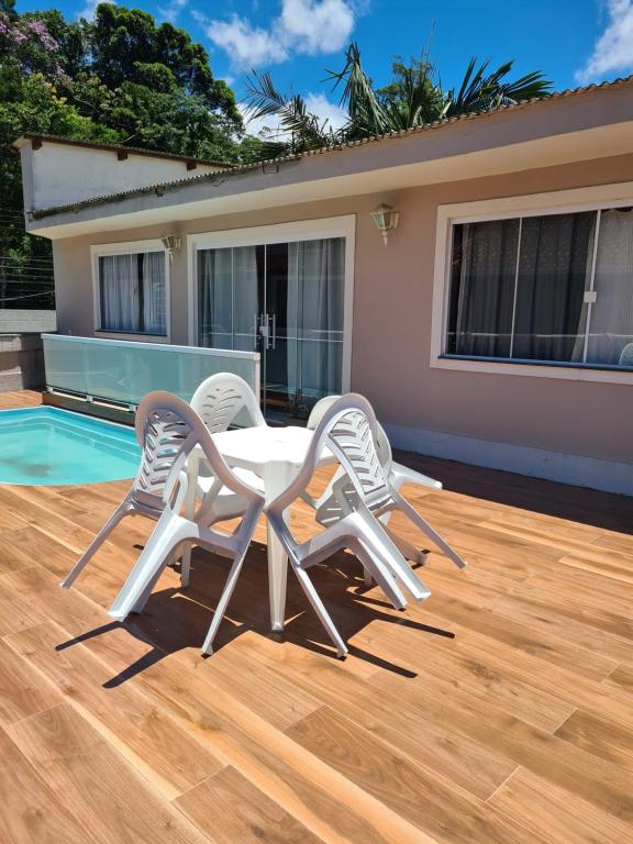 - 2 chaises et une table sur une terrasse à côté de la piscine dans l'établissement Hospedagem Doce Lar - Casa Manacá, à Teresópolis