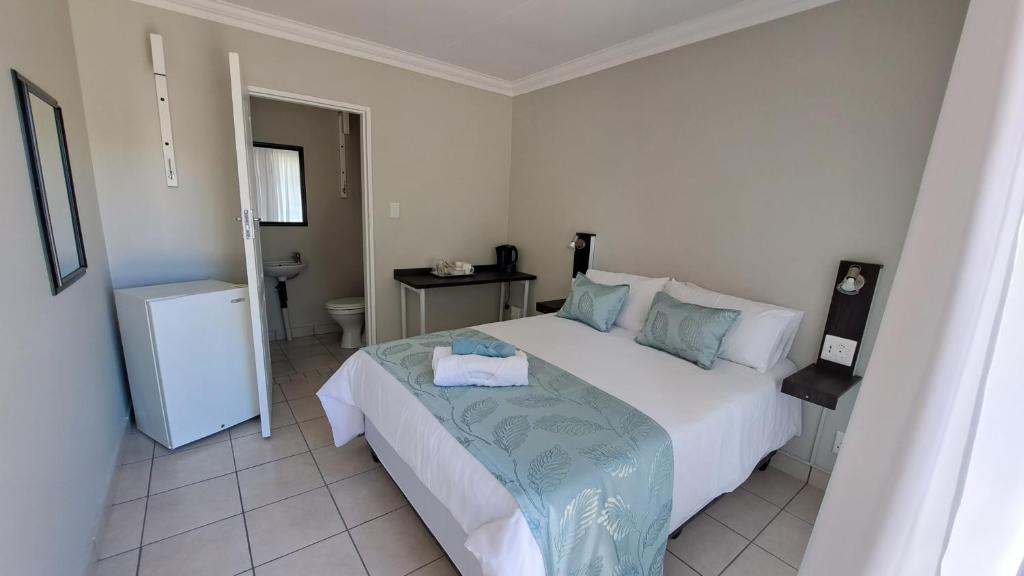 a bedroom with a large white bed and a bathroom at Chrisserus Guest Rooms in Bloemfontein