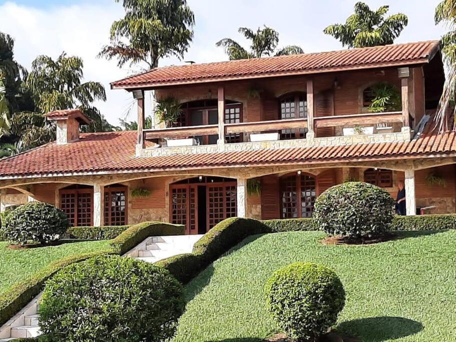 a large house with a large yard with bushes at Linda Chácara em Piracaia SP in Piracaia